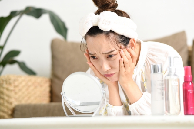 女性が鏡で顔を見て悩んでいる