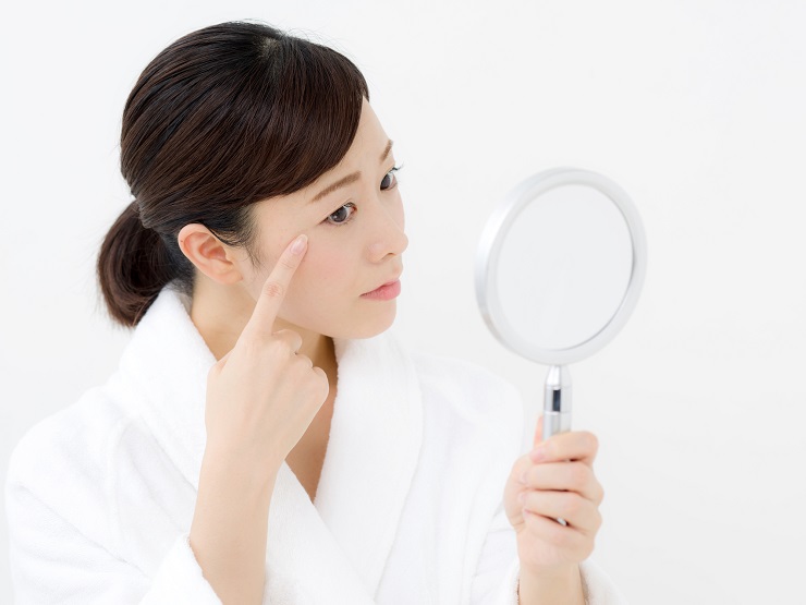 鏡を見て目元を触っている女性