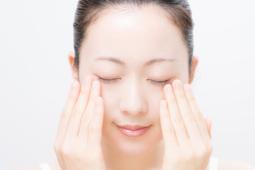 目を閉じて手を目に当てている女性