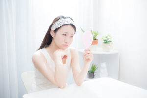 鏡を見ながら、悩んでいる女性