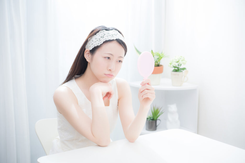 鏡を見ながら、悩んでいる女性