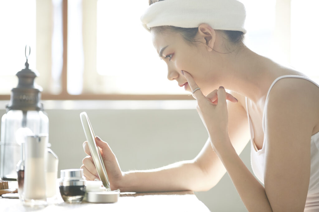 鏡を見て目の下に手をあてている女性の横顔