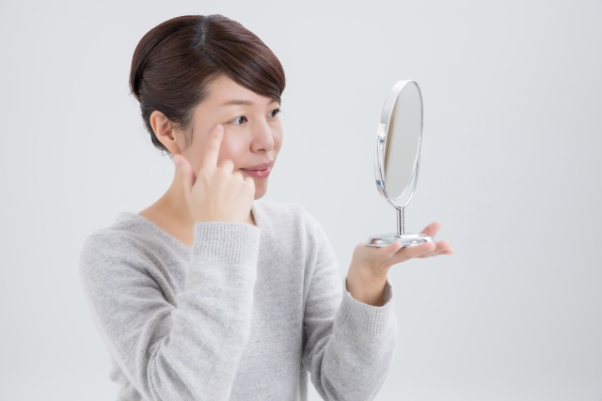 鏡で目元を確認する女性